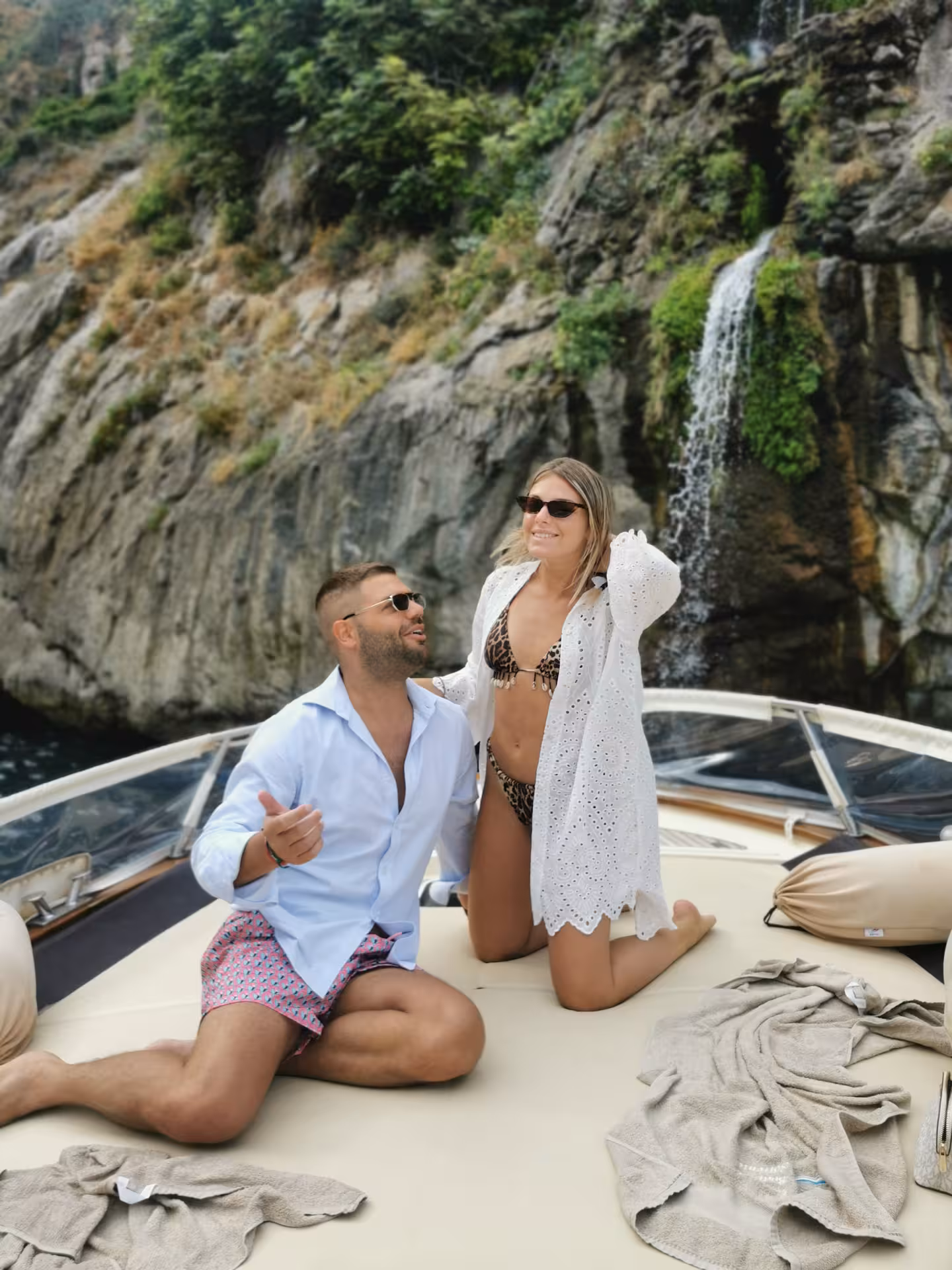 Couple relaxing on a boat with a scenic waterfall backdrop during a Sorrento to Positano private tour.