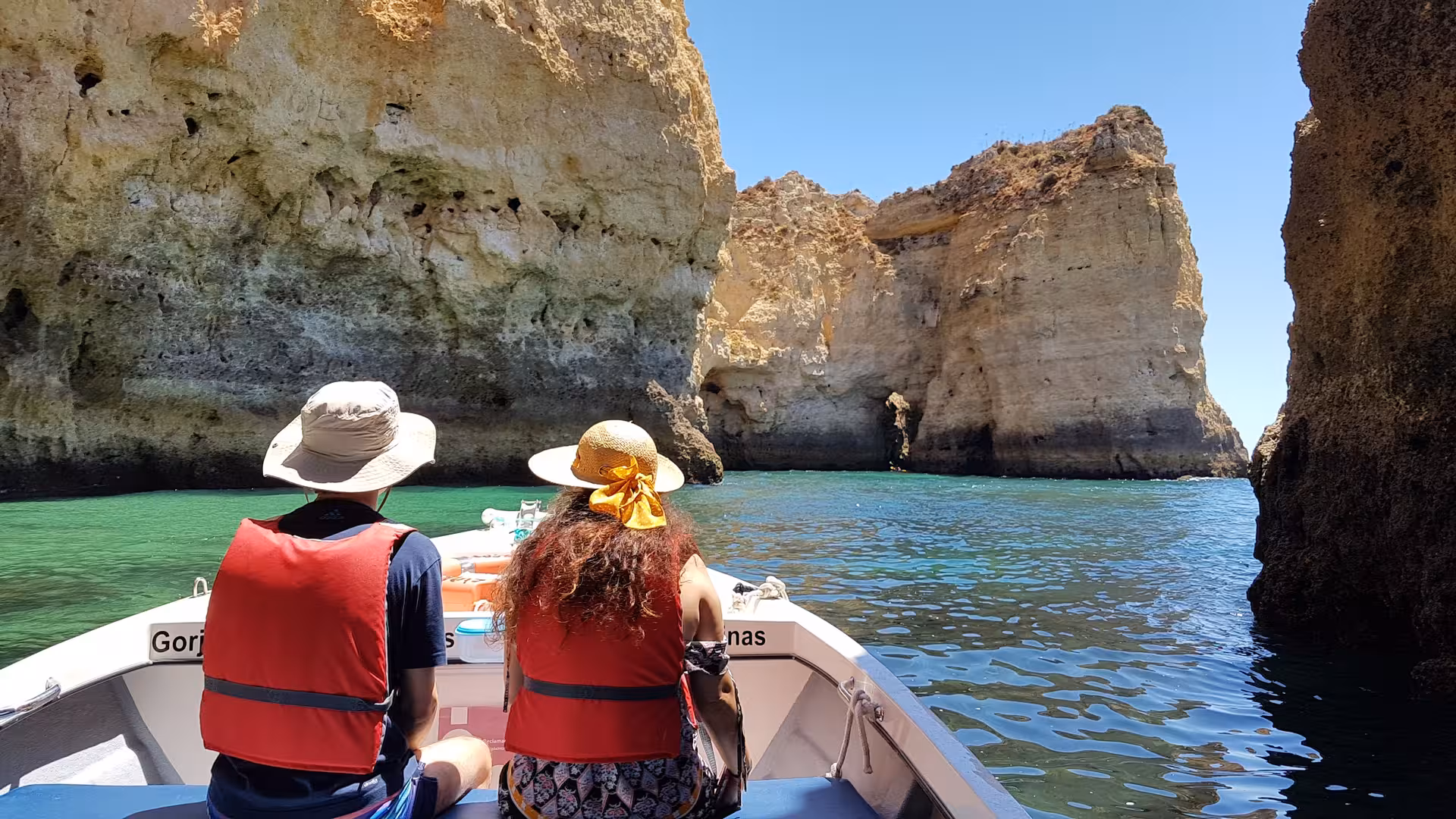 Couple on a Lagos Algarve boat trip to Ponta da Piedade, cruising past golden cliffs and clear turquoise Atlantic water