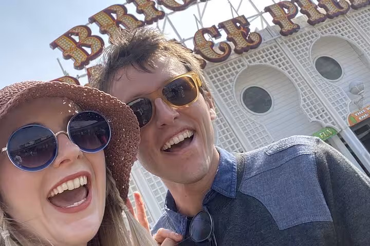 Happy couple smiling at Brighton Palace Pier entrance on a sunny day