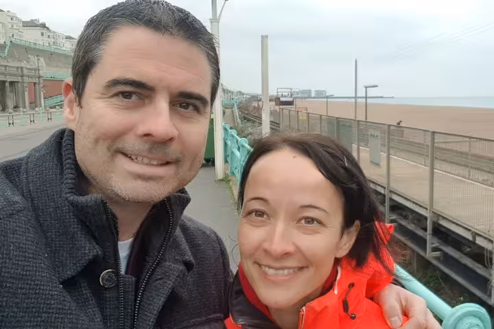 Couple smiling on Brighton seafront promenade during a self-guided walking tour