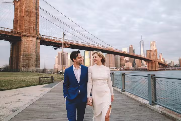 Couple walks hand in hand by Brooklyn Bridge, capturing memorable moments on New York photo tour.