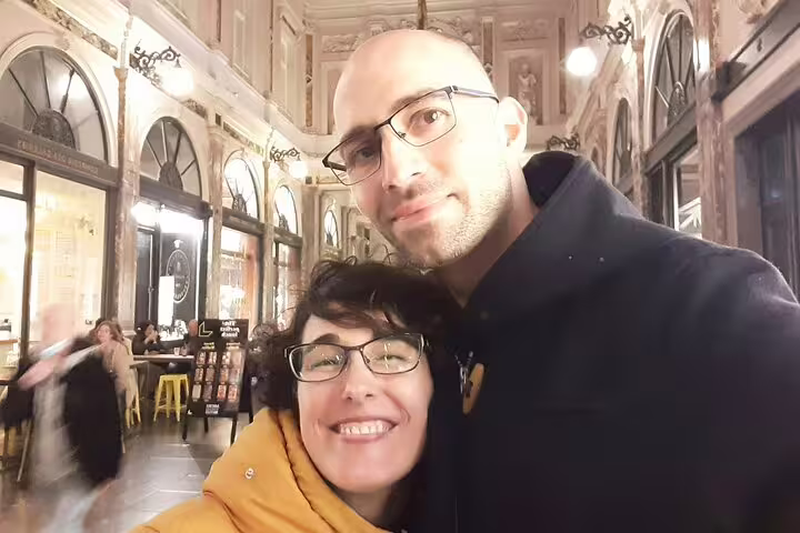 Couple smiling during self-guided walking tour in Brussels historic arcade at night