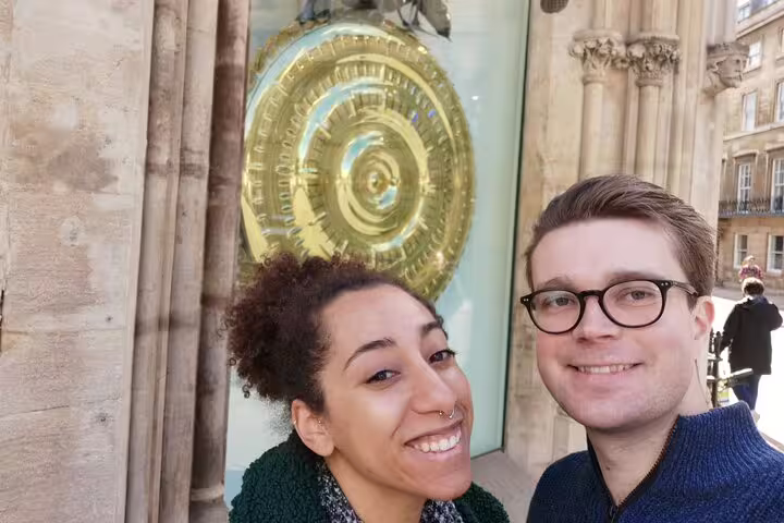 Couple smiling in front of the Corpus Clock in Cambridge city centre