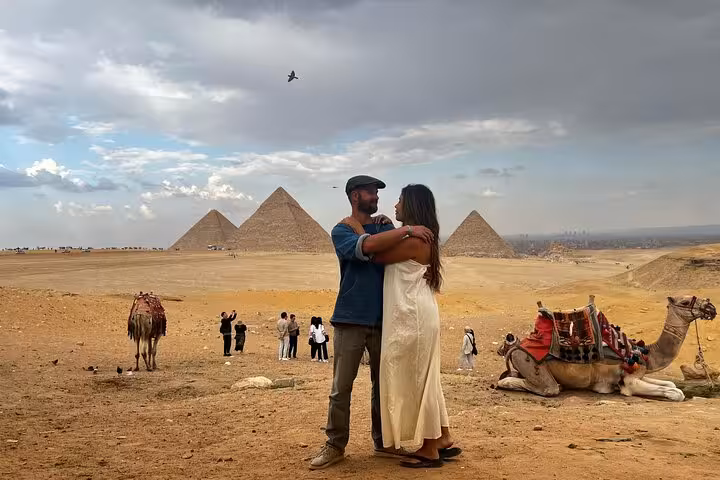 Couple embracing with camels and Giza Pyramids backdrop on skip-the-line hidden gems tour for epic photos
