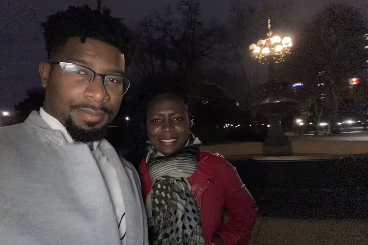 Couple smiling together at night in Central Park with decorative lamp post in background