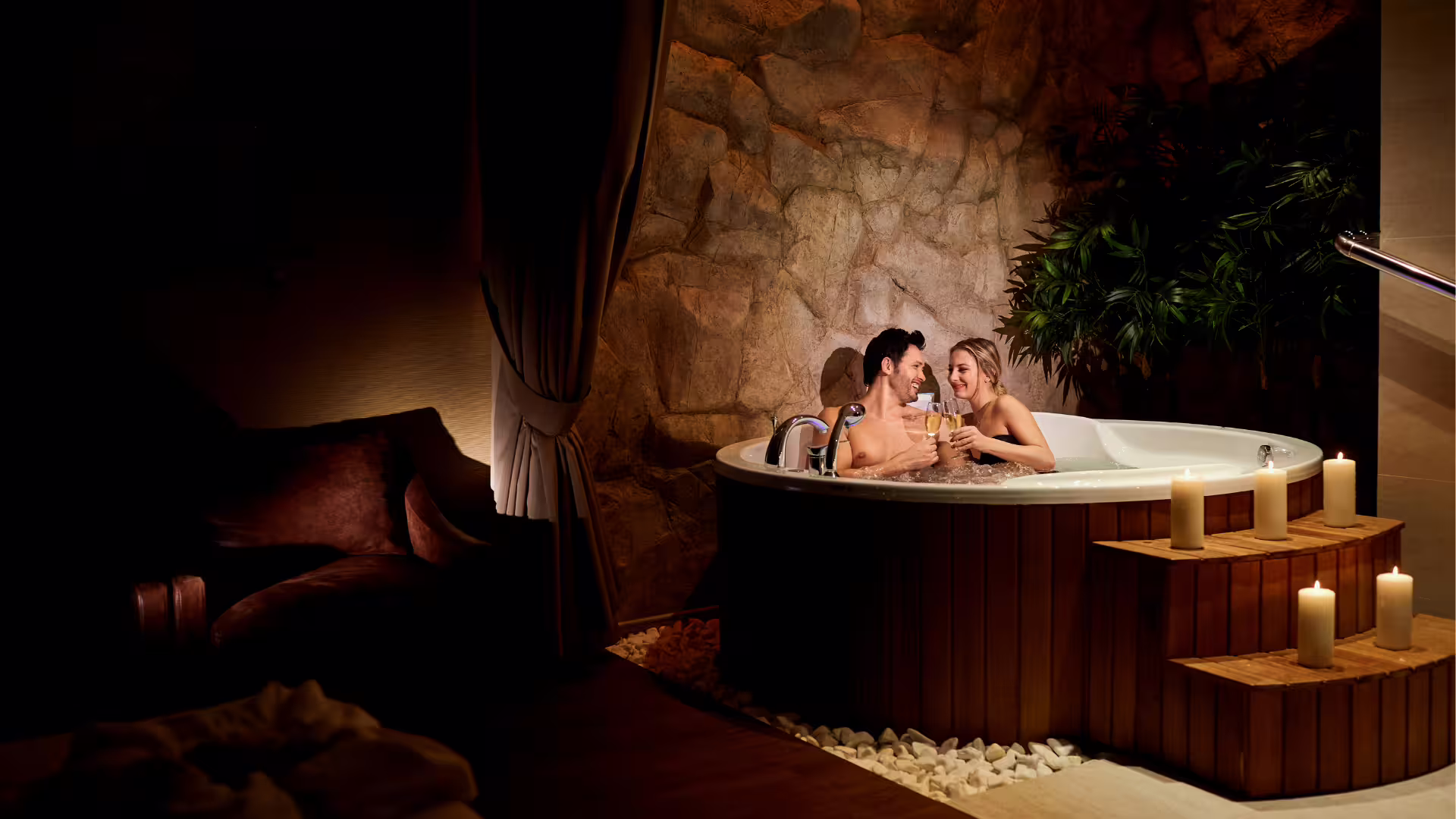 Couple toasting champagne in private jacuzzi spa suite with candles during romantic Solofra escape and wellness retreat