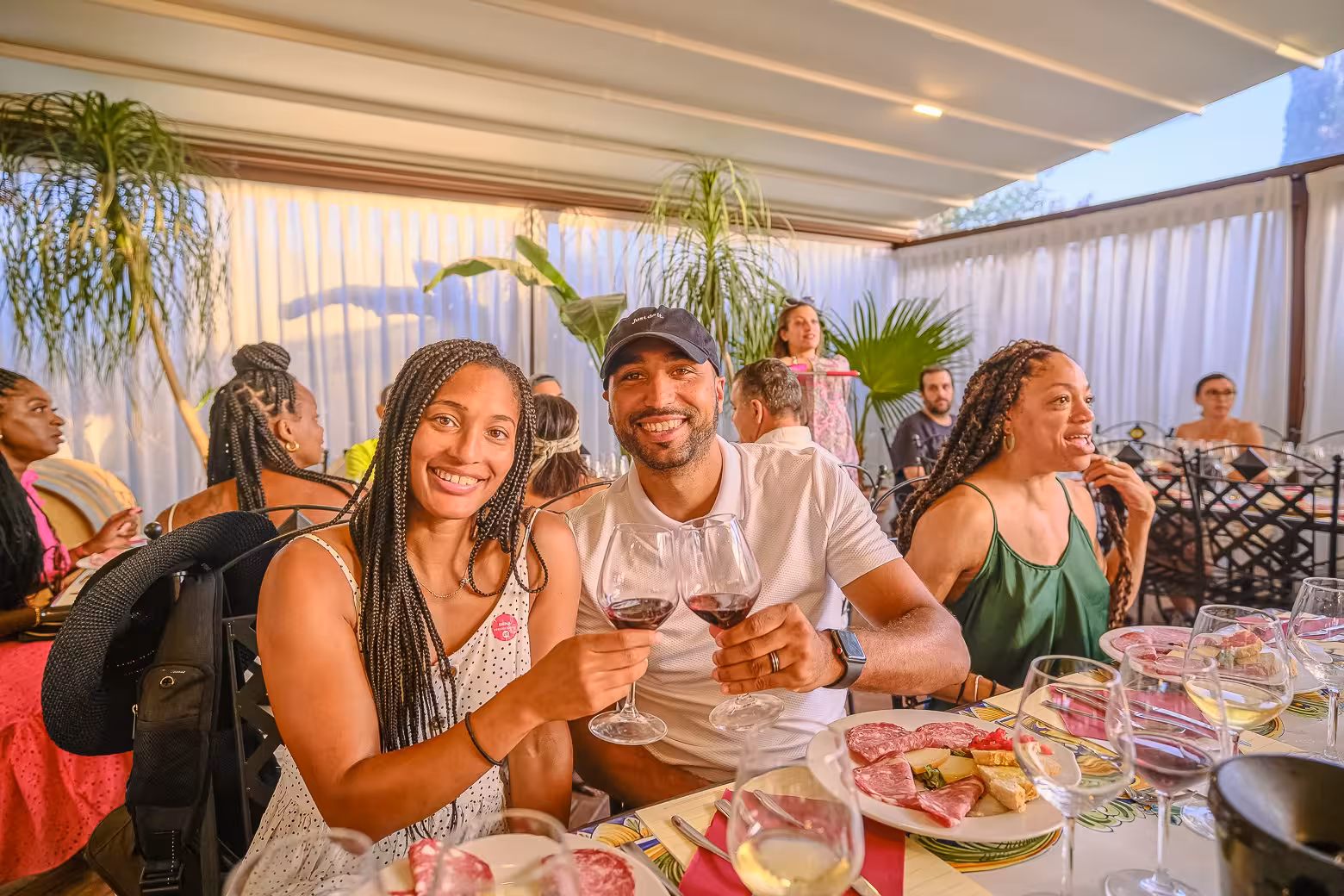 Couple enjoying wine and charcuterie at a Chianti winery tour dinner, smiling at an outdoor dining table.