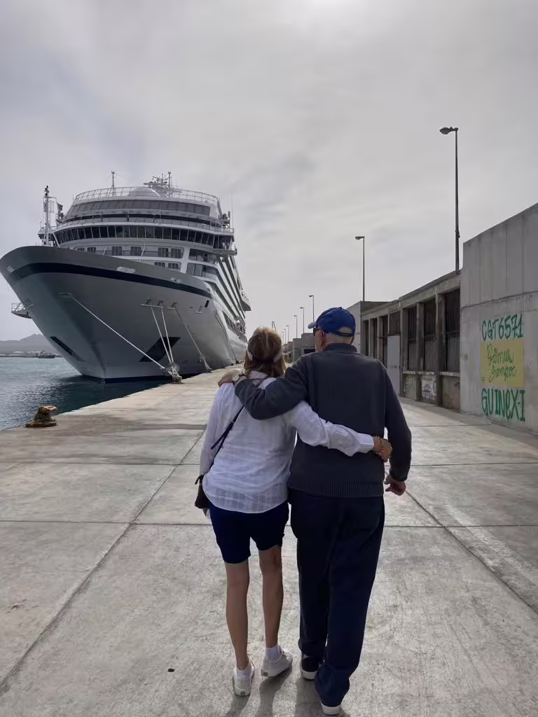 Couple walking towards cruise ship in Mindelo harbor, São Vicente, enjoying a full-day shore excursion with scenic highlights.
