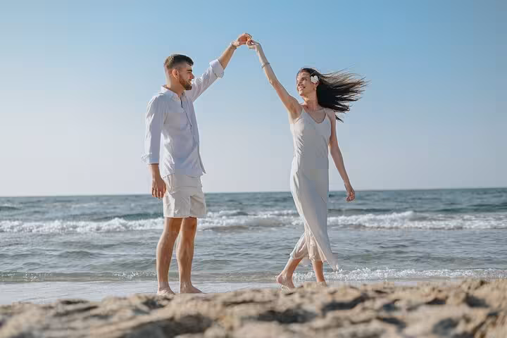 Couple dancing joyfully on the beach during a private photoshoot in Anisaras.