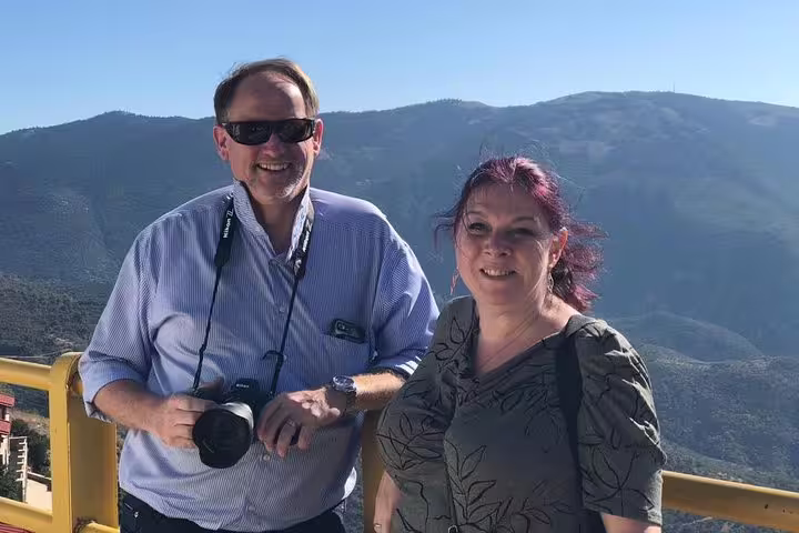 Couple enjoying a scenic view of the mountains during a private day trip from Athens to Delphi, perfect for photography enthusiasts.