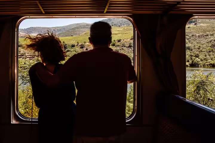 Couple admiring vineyard landscapes from a train window on a Douro Valley experience tour.