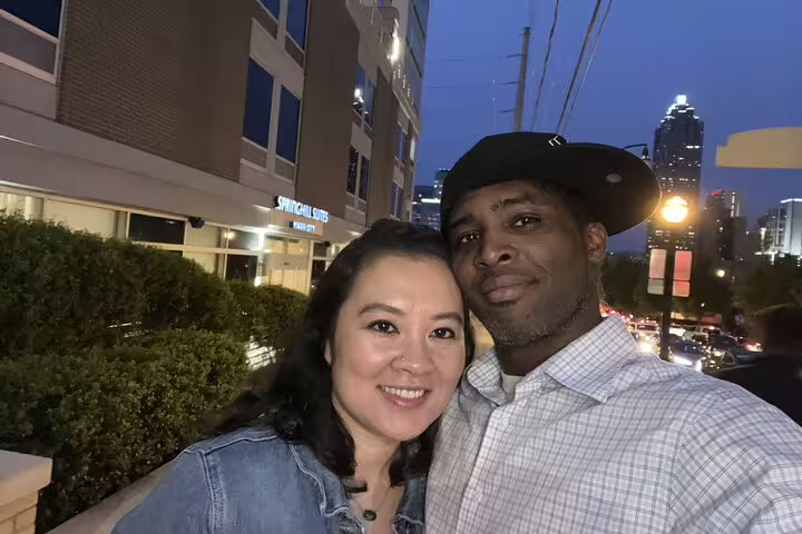 Couple smiling together on Downtown Atlanta Walking Tour at dusk with city skyline in background