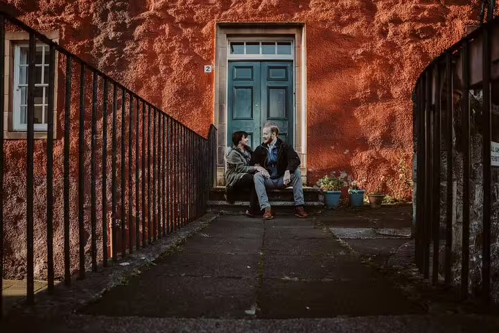 Couple sitting by colorful Old Town doorway during private Edinburgh photoshoot with a professional photographer