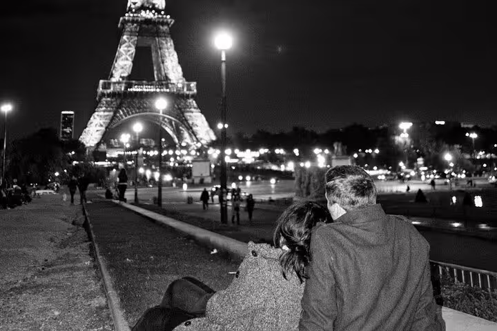 Couple sitting together at night admiring the illuminated Eiffel Tower in Paris