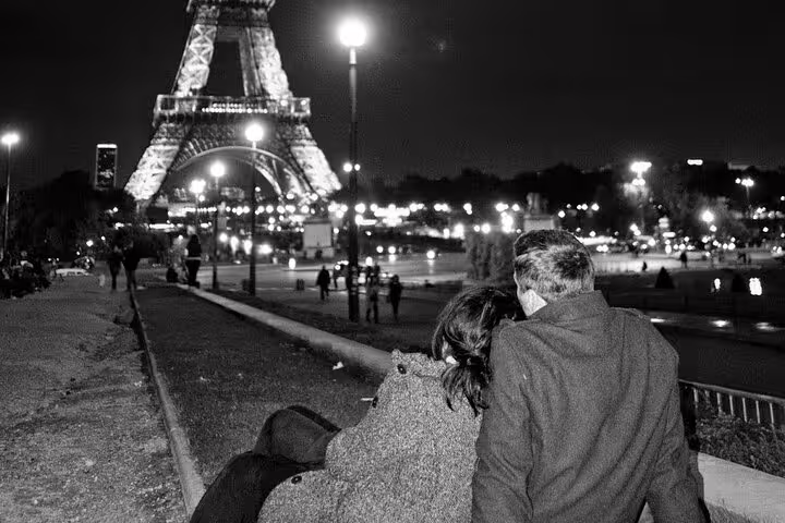 Couple sitting together at night admiring the illuminated Eiffel Tower in Paris