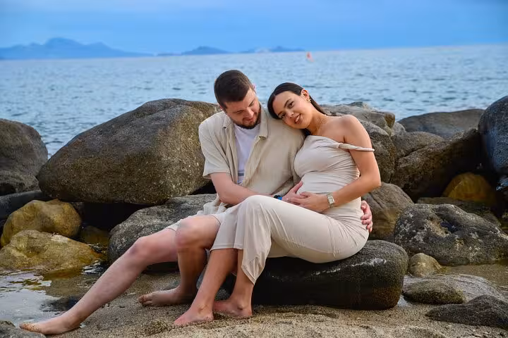 Couple embracing on rocky Analipsi beach during private photoshoot, capturing serene coastal moments.