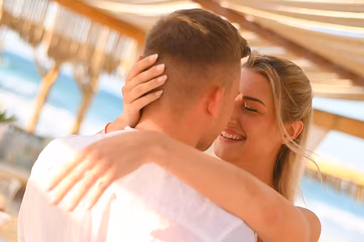 Joyful couple embracing under a pergola by the sea during a private photoshoot in Hersonissos.