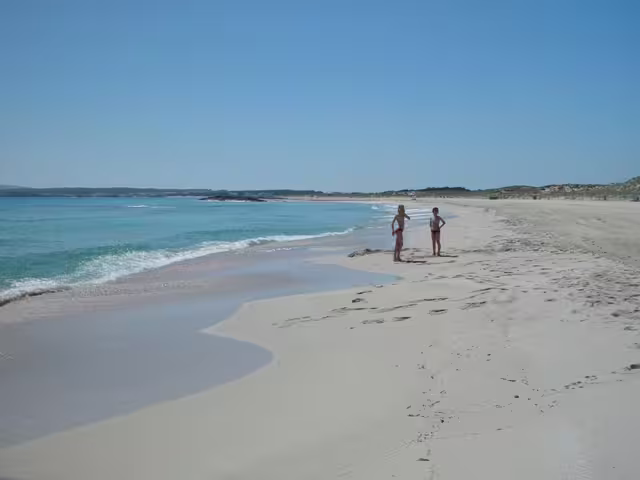 Couple strolling along Formentera shoreline on Ibiza to Formentera day trip with fast ferry, transfers and beaches