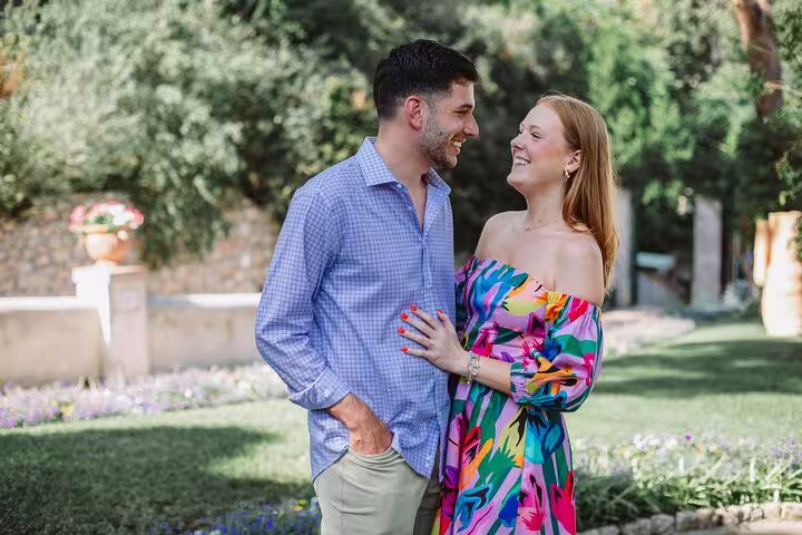 Smiling couple enjoying a moment in a lush garden during a private photoshoot in Naples with a professional photographer.