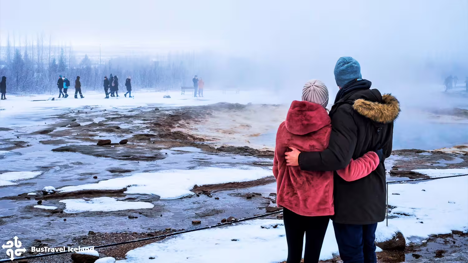 Couple embracing at Geysir geothermal area in winter, Golden Circle Iceland