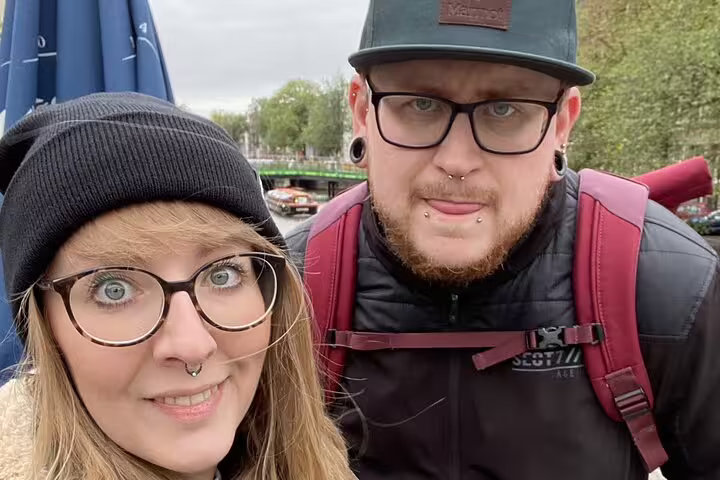 Two travelers with glasses and piercings posing outdoors in Amsterdam on a ghost walking tour