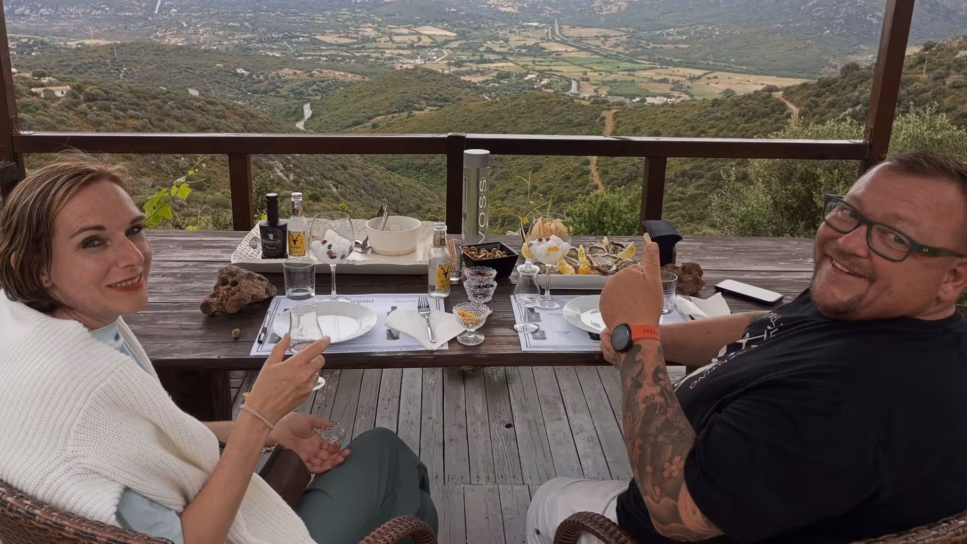 Couple enjoying gin tasting with panoramic views at a scenic Olbia distillery tour.