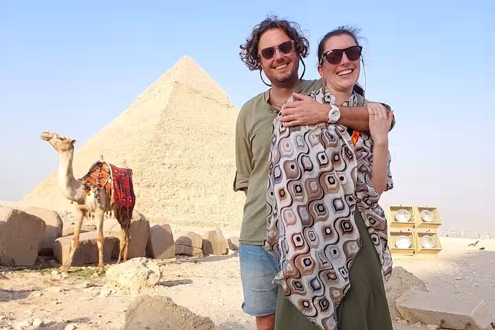 Couple posing by the Great Pyramid at Giza with camel nearby, Cairo day tour featuring ATV ride and felucca sail