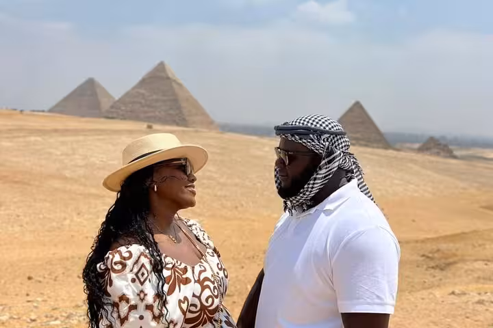 Couple posing with Giza pyramids in the desert on a private Cairo tour with Sphinx and Grand Egyptian Museum