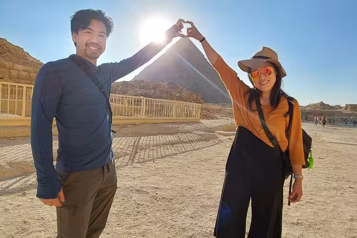 Couple framing the Pyramid of Giza with hands at sunrise on Cairo airport layover tour to Giza Pyramids
