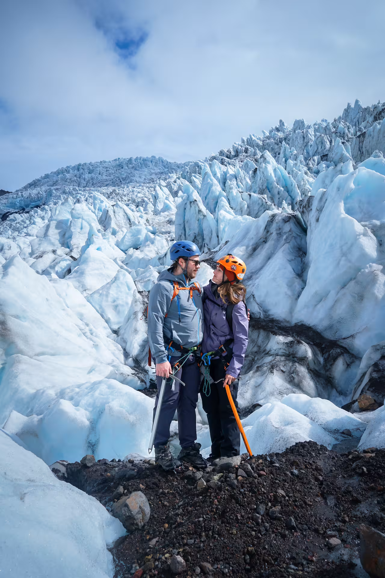 Couple with helmets and ice axes on Iceland glacier hike surrounded by dramatic blue ice formations