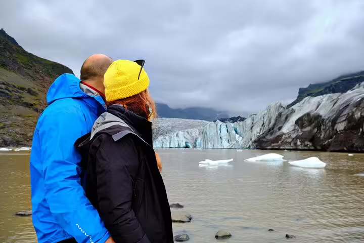 Couple viewing glacier lagoon with floating icebergs on Iceland South Coast tour