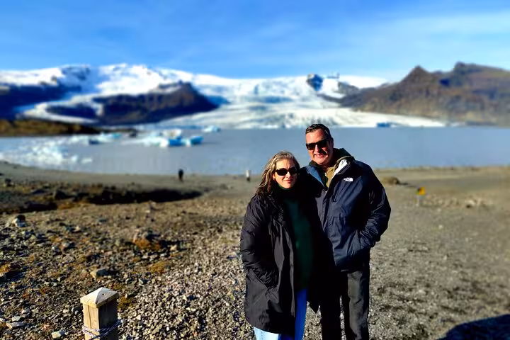 Couple posing at Jökulsárlón glacier lagoon with icebergs and glacier on Iceland's south coast