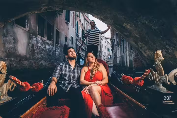 Couple in gondola under a Venice bridge captured on a private travel photographer tour with gondolier