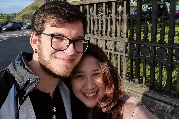 Couple smiling together near ornate iron gate on Edinburgh walking tour
