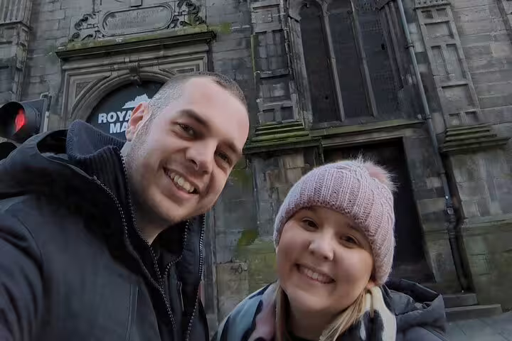 Couple smiling in front of historic Gothic stone building on Edinburgh's Royal Mile