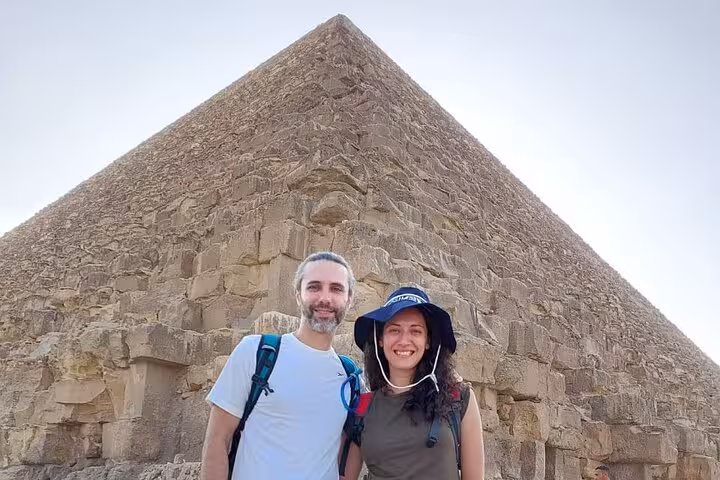 Couple at base of Great Pyramid of Giza on all-inclusive private day trip from Cairo Airport with transfers