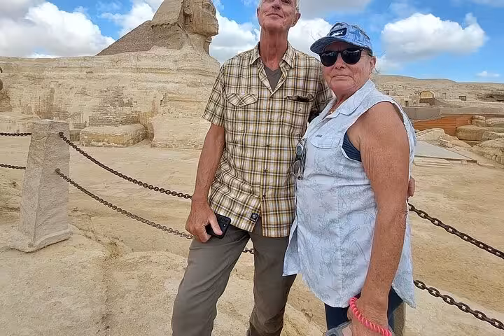 Couple posing near the Great Sphinx of Giza on a private full-day trip including pyramids and museum