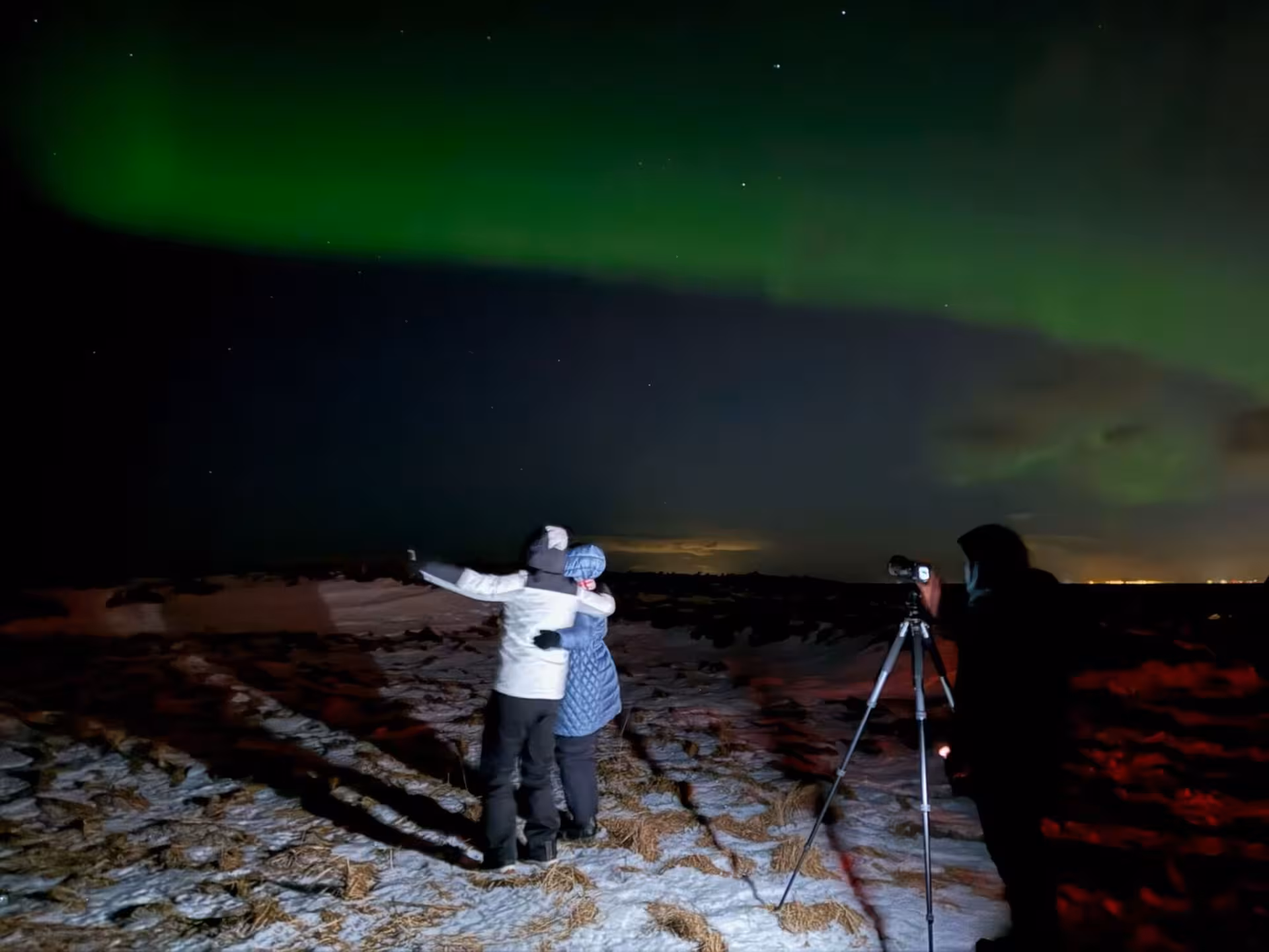 Couple embracing under vivid green northern lights on a private 4x4 Iceland aurora tour from Reykjavik