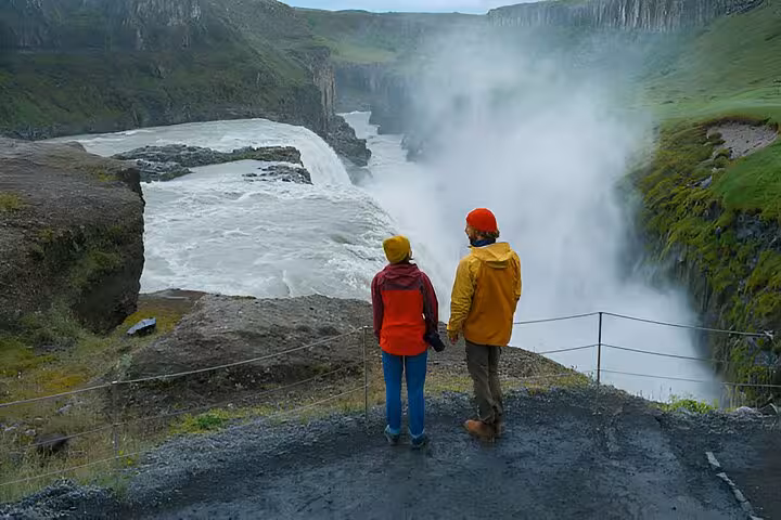 Couple in colorful rain jackets viewing Gullfoss waterfall on Golden Circle tour from Reykjavik