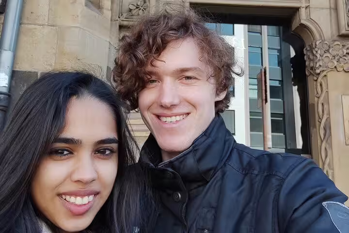 Couple smiling in front of historic stone building in Cologne during walking tour