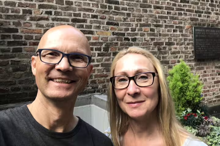 Couple smiling in front of historic brick wall in Cologne on haunted witch quest tour