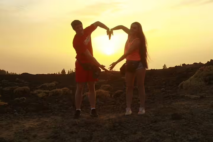 Couple forming a heart with their hands during a scenic Teide sunset quad trip, capturing the romantic volcanic landscape.