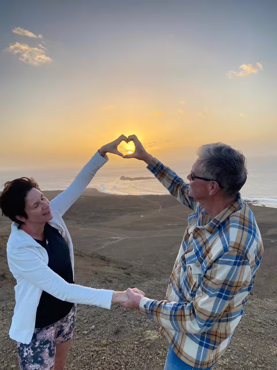 Couple making heart shape around the sun at Mount Lion during sunset hike, romantic coastal viewpoint photo stop