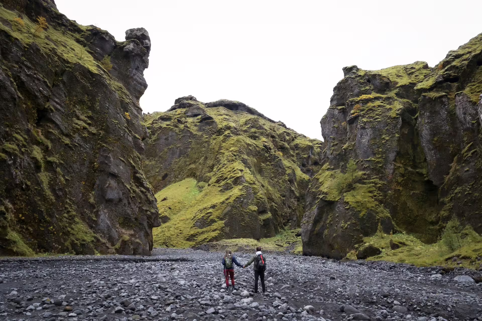 Couple hiking through a dramatic moss-covered Iceland canyon on an epic 12-day Grand Tour adventure