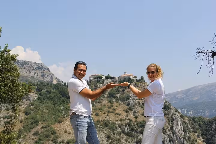 Couple posing with hilltop village backdrop on countryside tour from Cannes