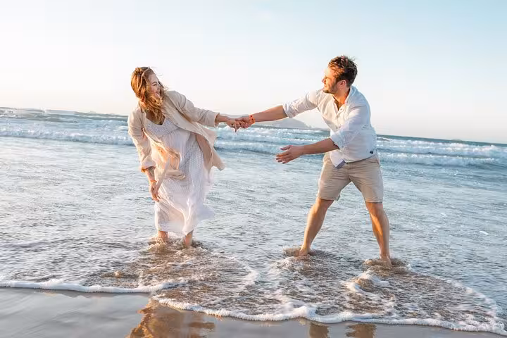 Joyful couple holding hands in the waves of Heraklion beach, perfect for a romantic photoshoot session.