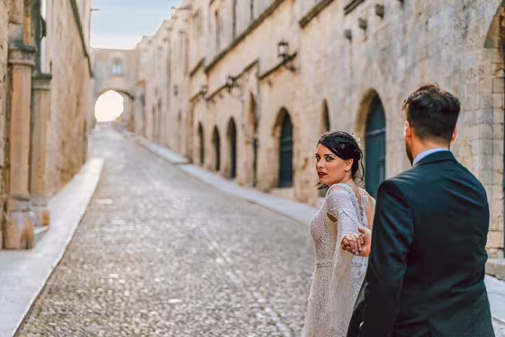 Couple holding hands walking down the cobbled streets of Rhodes, showcased in a professional photoshoot setting.