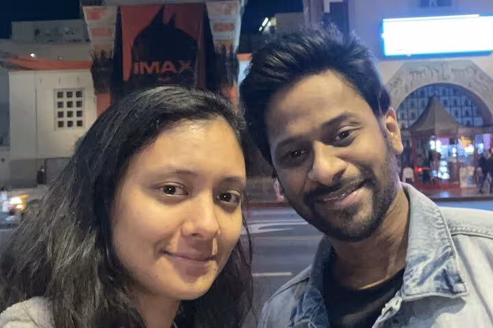 Couple smiling at night near Hollywood IMAX theater during ghost hunt walking tour
