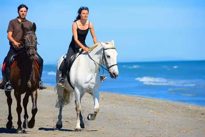 Couple riding horses along the Red Sea beach in Hurghada, part of a 3-hour swim with horses tour