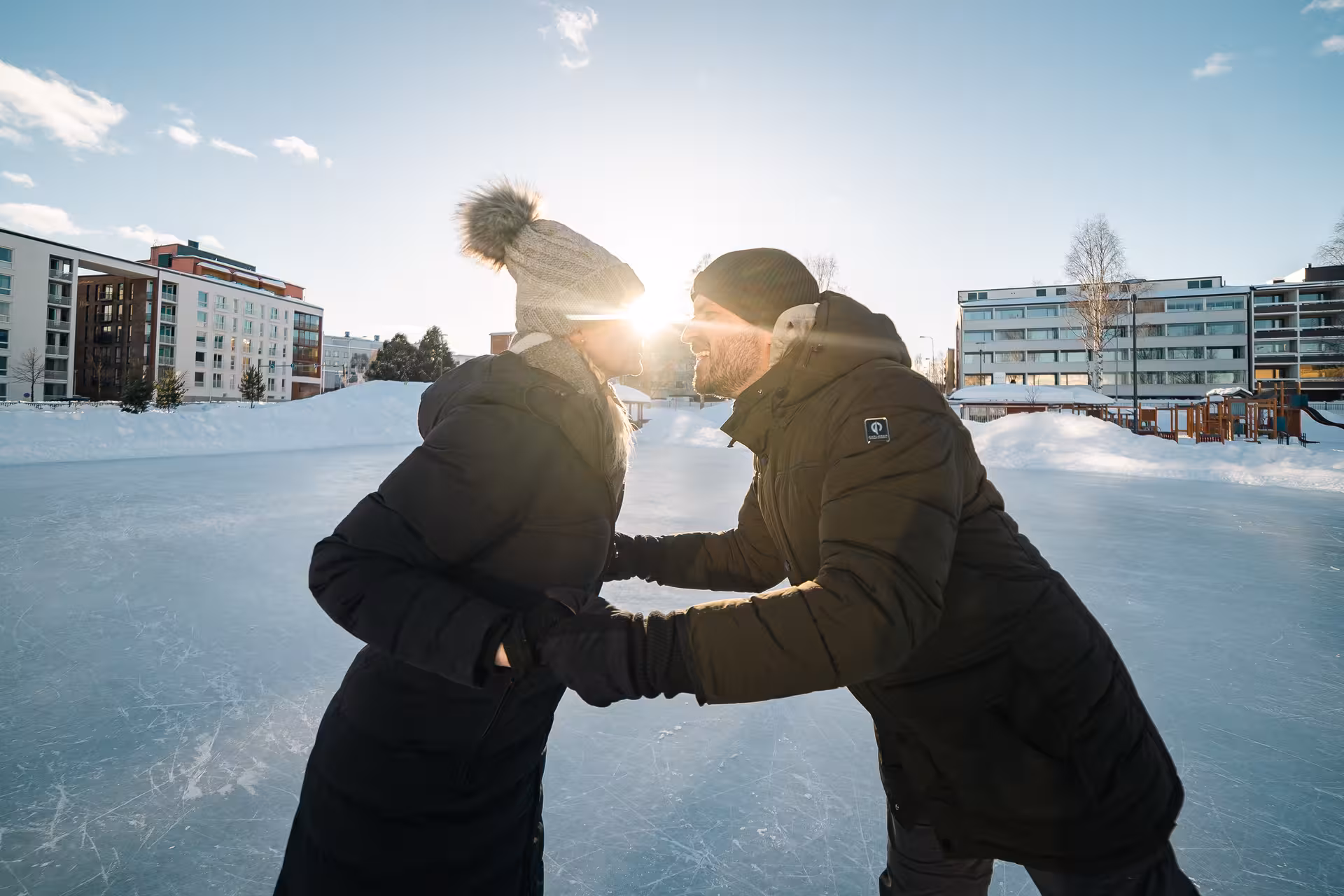 Couple enjoying a romantic ice skating session in Rovaniemi, captured with the sun setting behind them on the rink.